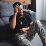 Veteran sitting on the floor holding his head in pain from a migraine
