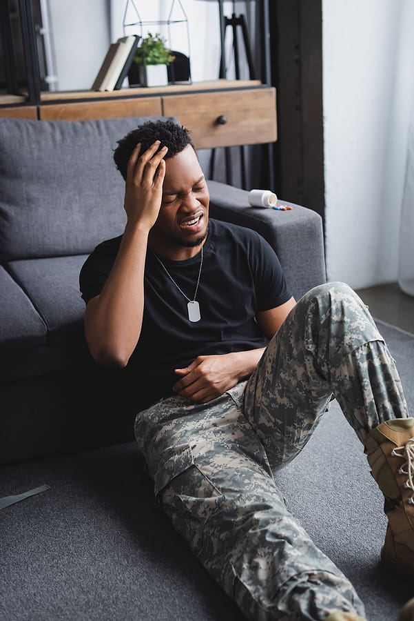 Veteran sitting on the floor holding his head in pain from a migraine