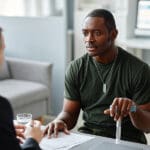Young veteran with cane and a disability rating protected under the va five ten and twenty year rules speaks to a doctor