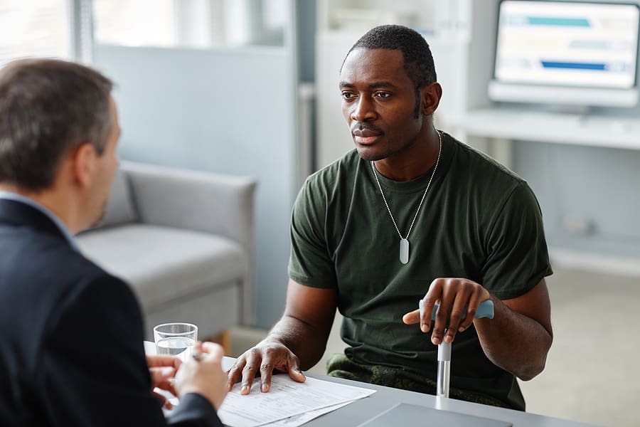 Young veteran with cane and a disability rating protected under the va five ten and twenty year rules speaks to a doctor