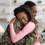 Mom in military uniform hugging young daughter