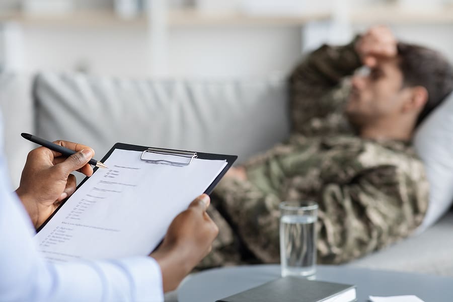 Doctor takes notes while veteran lays on couch talking about a secondary mental health condition