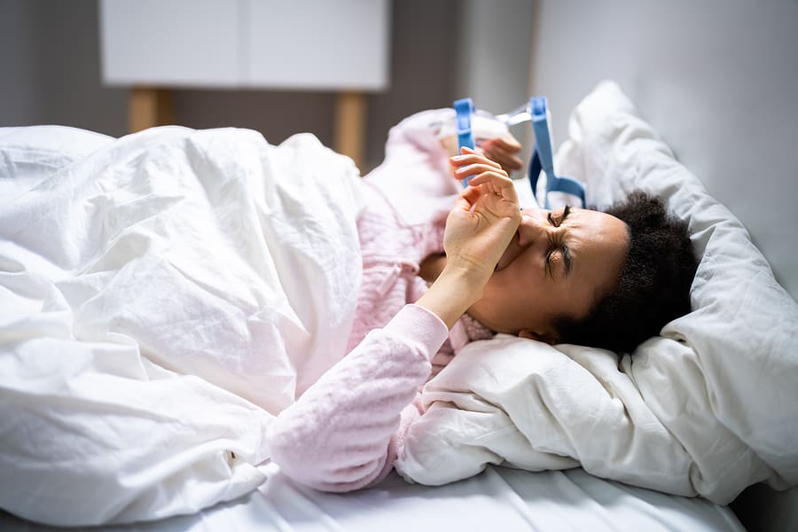 Young veteran with sleep apnea waking up and taking off her CPAP mask