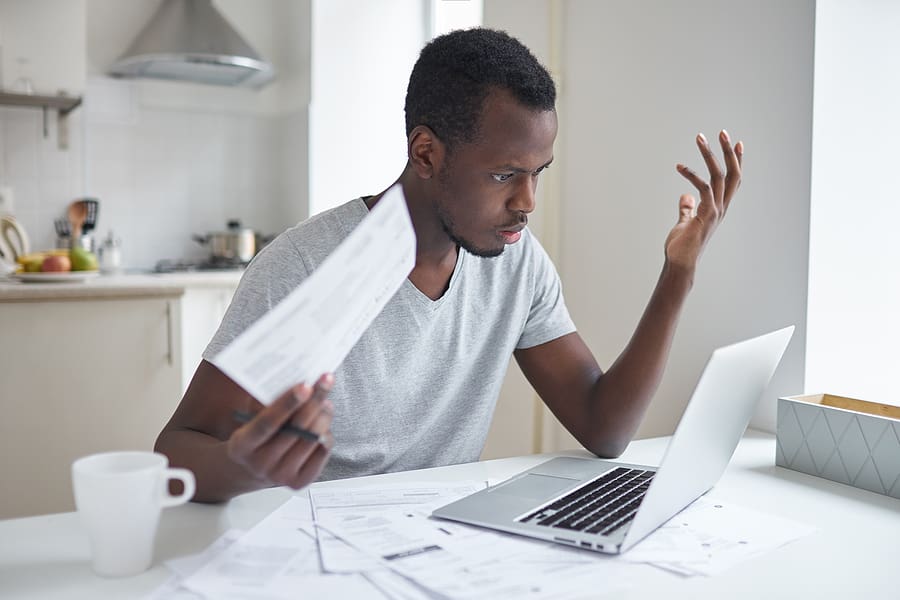 Veteran looking frustrated while holding paperwork for a VA claim appeal and looking at his laptop