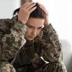 Young veteran with PTSD holding her head in her hands because she is upset