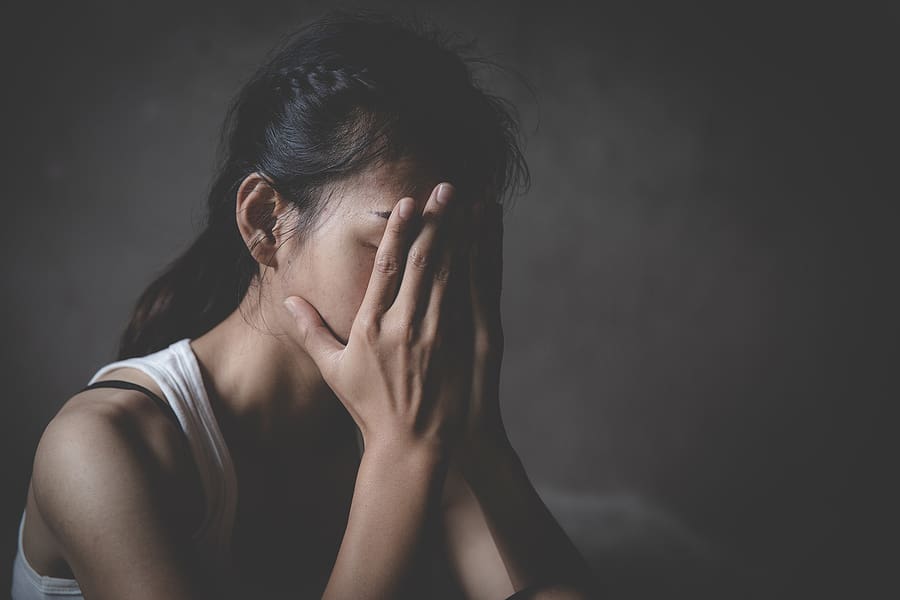 Young female veteran covering her face while dealing with the effects of sexual assault