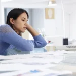 Stressed veteran surrounded by paperwork trying to understand why her VA claim was denied