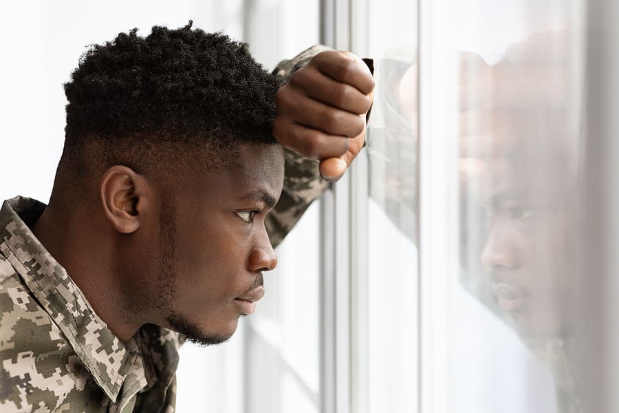 Young veteran with service related disability staring sadly out of a window