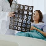 Doctor speaking to veteran about her brain cancer scans in a hospital room