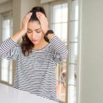 Young female veteran holding her head in pain due to a headache