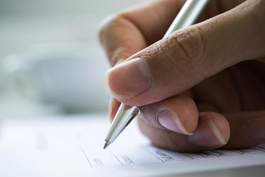 Close up of a veterans hand filling out paperwork for a VA disability claim