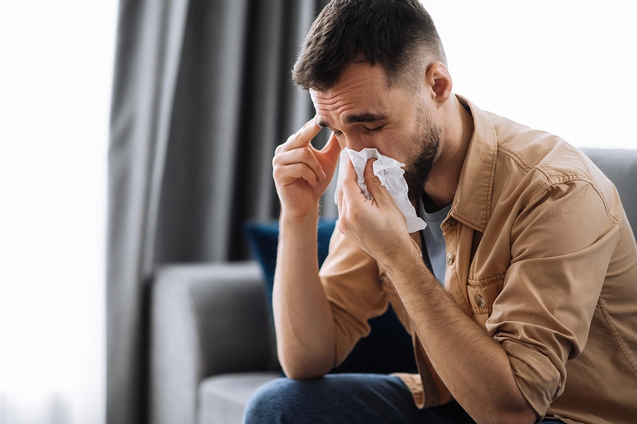 Young male veteran with a sinusitis VA rating sitting at home on his couch dealing with a painful sinusitis episode