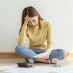 Young female veteran sitting on the floor surrounded by paperwork trying to determine the effective date for her VA disability claim