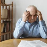 Older male veteran at his kitchen table looking at paperwork for a claim to increase his VA disability rating