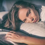 Young female veteran laying in bed during the day looking exhausted due to chronic fatigue syndrome