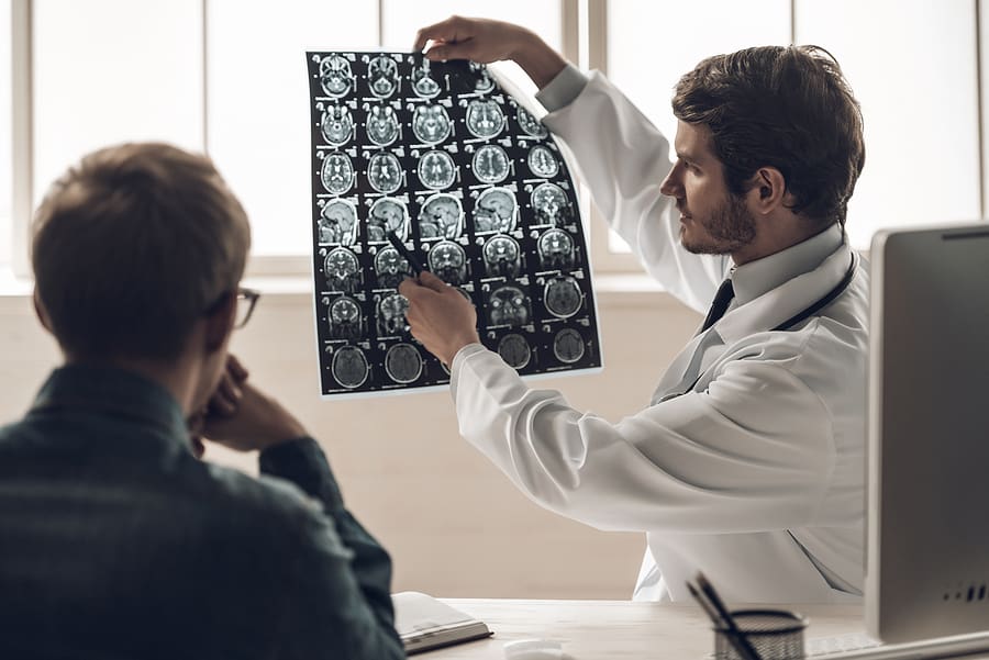 Doctor holding a brain scan explaining the results to a veteran with a traumatic brain injury
