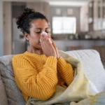 veteran with a va rating for allergic rhinitis blowing her nose in a tissue